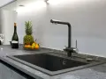 Nowoczesny zlew z baterią, obok ananas, mandarynki i butelka wina. Blat z HPL, co to jest? To trwały materiał.