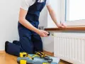 Instalator montuje termostat do grzejnika, pomagając wybrać między grzejnikiem stalowym czy aluminiowym.