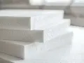 Stos styropianowych płyt, idealnych do izolacji. Zastanawiasz się, czym przykleić styropian do blachy? Wybierz odpowiedni klej!