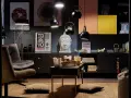 Salon w stylu eklektycznym z motywami azjatyckimi. Wygodne fotele, stolik z poduszkami, rzeźba Buddy i grafiki z Japonii tworzą przytulną atmosferę.