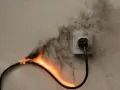 Płonący kabel podłączony do gniazdka. Dym unosi się na ścianie. Zastanawiasz się, ile gniazdek na jednym obwodzie to za dużo?