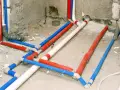 Instalacja wodna w domu: czerwone, niebieskie i białe rury tworzą skomplikowany system.