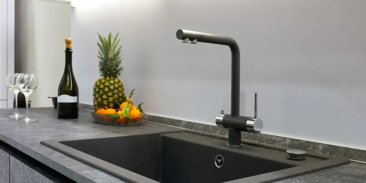 Nowoczesny zlew z baterią, obok ananas, mandarynki i butelka wina. Blat z HPL, co to jest? To trwały materiał.