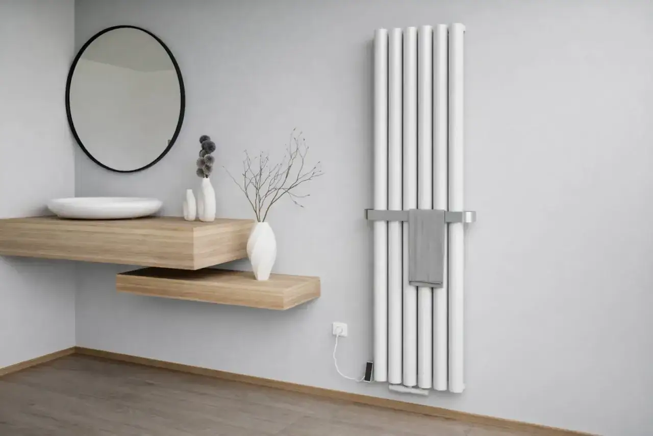 Nowoczesna łazienka z białym grzejnikiem stalowym lub aluminiowym, umywalką nablatową i lustrem.