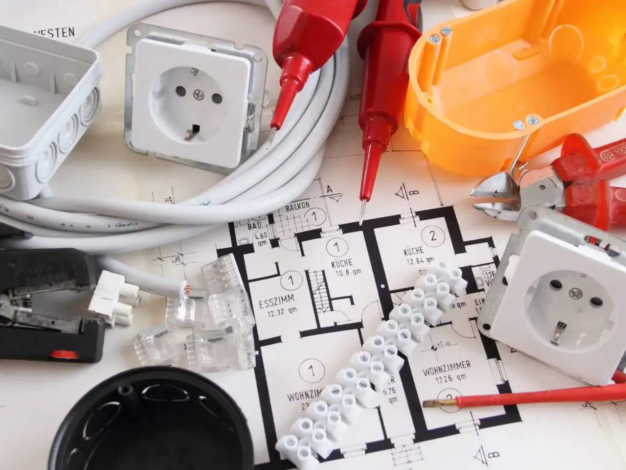 Materiały elektryczne na planie mieszkania: gniazdka, przewody, złączki. Zastanawiasz się, ile gniazdek na jednym obwodzie jest bezpieczne?